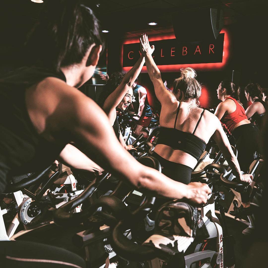 Two riders high-fiving during a CycleBar class
